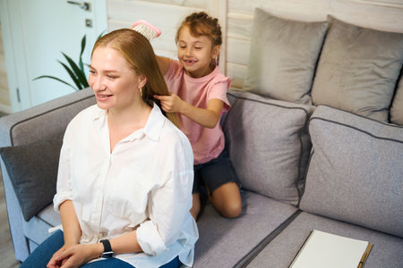 Little smiling girl learning how to comb and braid hair