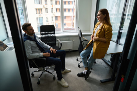 Woman manager communicates with a male colleague in small officeの写真素材