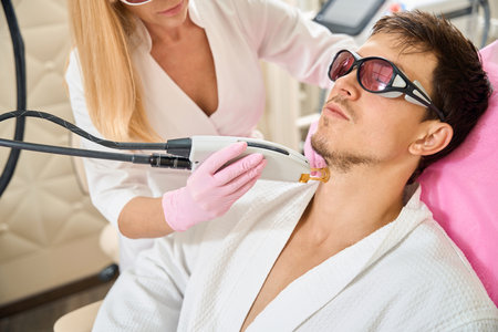 Man, client of beauty salon undergoing laser hair removal procedureの写真素材