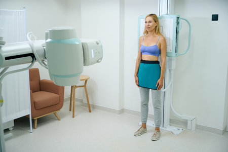 Mature female patient is undergoing thorax radiography in upright positionの写真素材