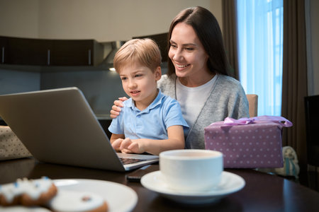 Woman watching Christmas movie with son enjoy buying presents in web storeの写真素材