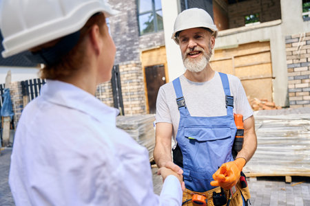 Friendly building contractor greeting site manager with handshake outdoorsの写真素材