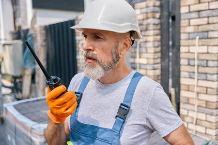 Construction worker using walkie-talkie on building siteの写真素材