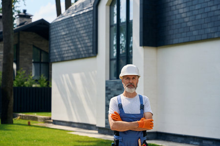 Confident construction worker standing in front of newly built cottageの写真素材