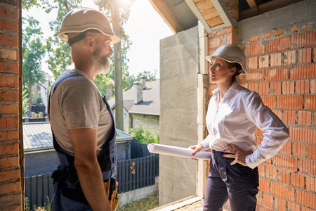 Construction supervisor having conversation with builder during site inspectionの写真素材