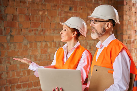 Construction specialists inspecting together unfinished dwelling house