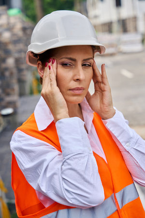 Tired building inspector suffering from tension headache on siteの写真素材