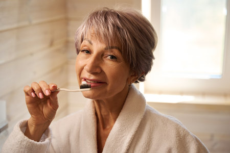 Elderly lady brushes her teeth with a toothbrush and toothpasteの写真素材
