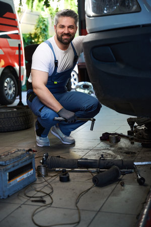 Joyful auto mechanic posing for camera while fixing client vanの写真素材