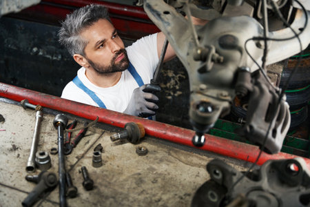 Skilled mechanic fixing car in inspection pitの写真素材