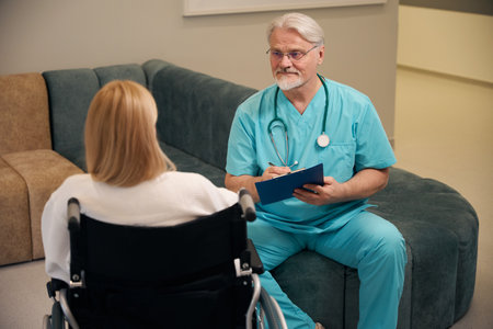 Clinician writing down female patient complaints in medical facility lobbyの写真素材