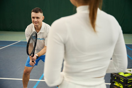 Man trainer teaching woman to hit ball effectively in their tennis workout