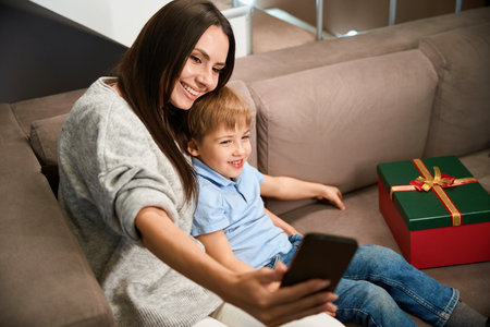 Smiling female with her son making selfie while celebrating Christmas holidays