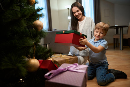 Woman celebrating Christmas with her son sharing presents X-mas tree in hotelの写真素材