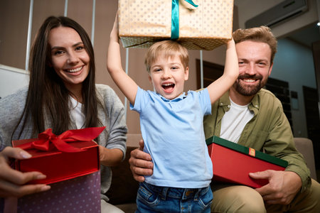 Happy little boy rejoicing New Year gifts while celebrating Christmasの写真素材