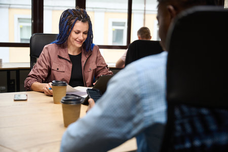 Multi-racial male and female colleagues working in comfortable office