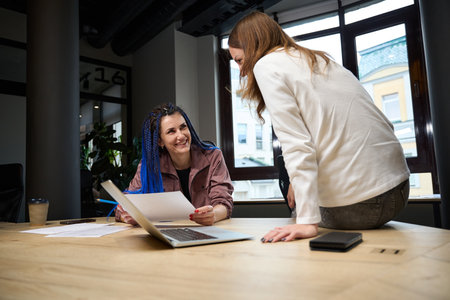 Smiling female colleagues whispering and conferring privately