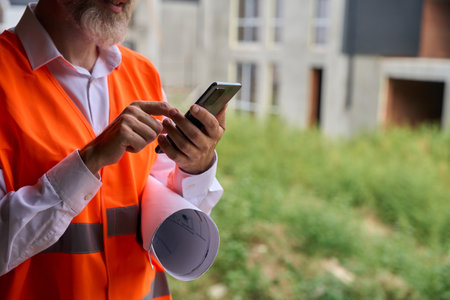 Foreman is using his cellphone on building site in morningの写真素材