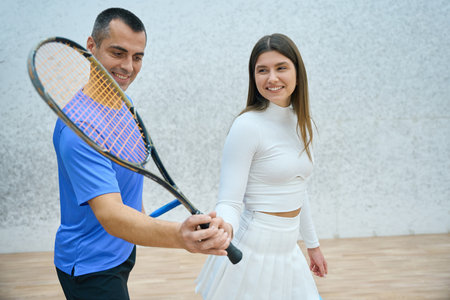 Man trainer enthusiastically demonstrates action of hitting ball in squash gameの写真素材