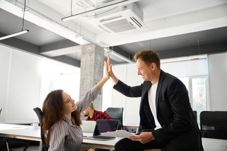 Man and woman interchanging high five after successful work plan discussion