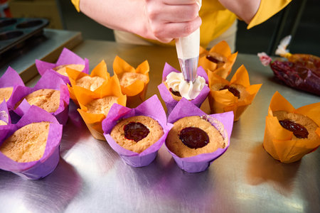 Experienced baker decorating dessert with white frosting on kitchen countertopの写真素材