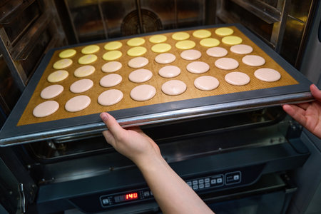 Experienced pastry chef is baking batch of biscuits in kitchenの写真素材