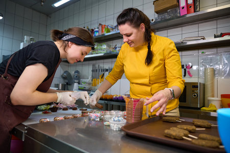 Team of pastry chefs decorating together cakesicles on kitchen countertopの写真素材