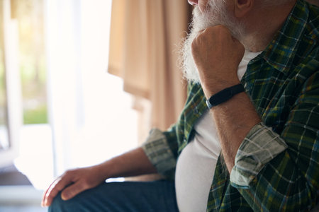 Lonely old man in checkered shirt is resting in cozy chairの写真素材