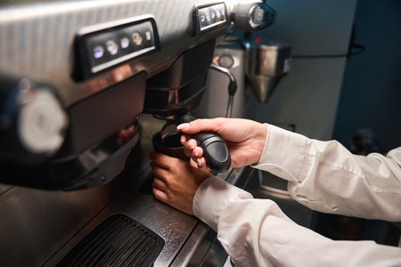 Barista in a white blouse prepares coffee in coffee machineの写真素材