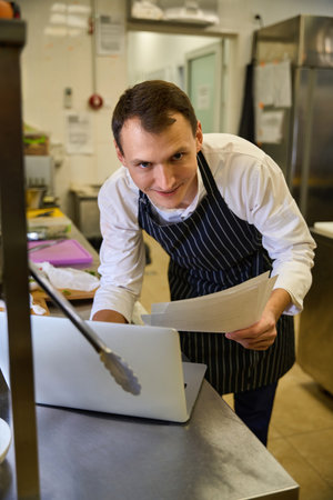 Kitchen employee works with documents at the kitchen rackの写真素材