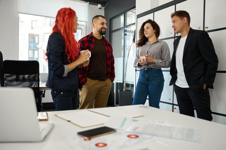 Friendly team of marketers resting and laughing during coffee break
