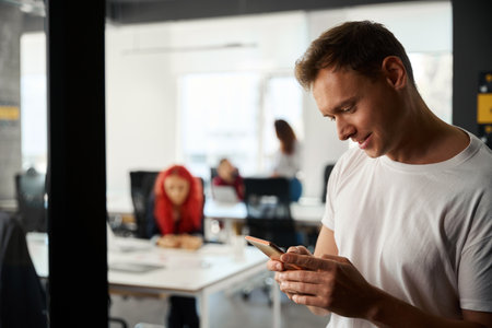Close-up handsome young man playing games on smartphone instead of workの写真素材