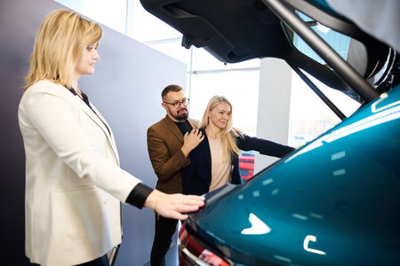 Two people inspecting the trunk of a blue carの写真素材