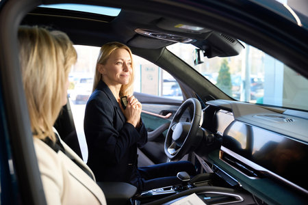 Happy woman sitting in a car hugs her keysの写真素材