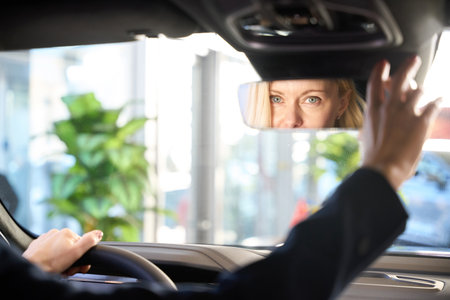 Caucasian woman adjusting rear view mirror in car