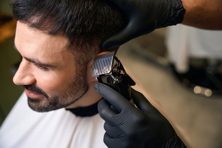 Barber using hair clipper for making stylish haircut for customerの写真素材
