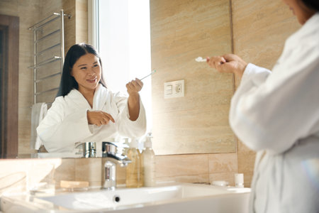 Cheerful lady having fun during tooth brushing in morning