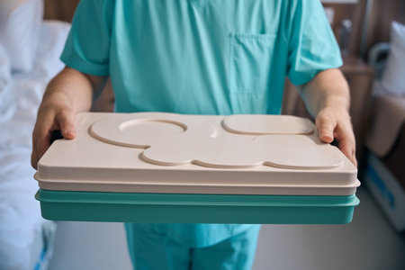 Nursing assistant serving meal to inpatient in medical facility ward