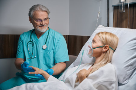 Doctor supporting inpatient during intravenous infusion procedure in wardの写真素材
