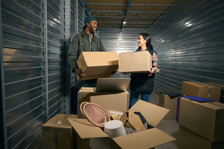Team of cheerful warehouse workers unloading goods together