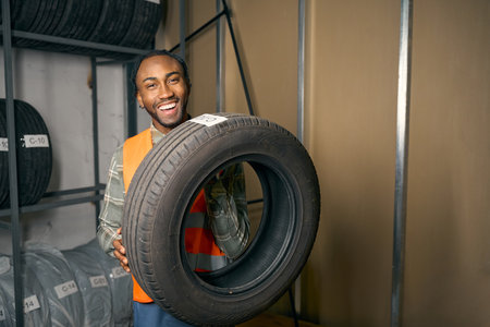 Cheerful young man arranging car tires in garageの写真素材