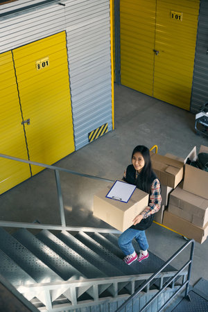 Joyous young storehouse worker carrying cargo upstairsの写真素材