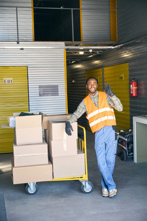Cheerful warehouse loader posing for camera during cargo unloading