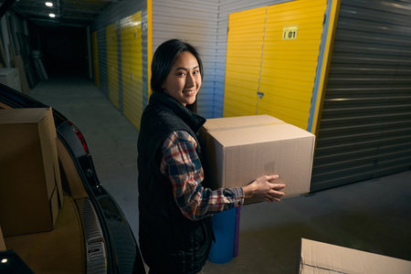 Woman unloads clothes from the trunk of a car in a storage service