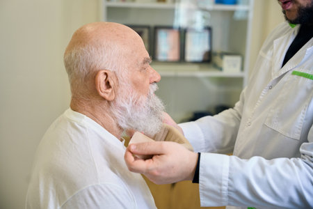 Adult doctor puts a lead collar on an old patientの写真素材