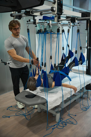 Elderly lady on a harness under the supervision of specialist