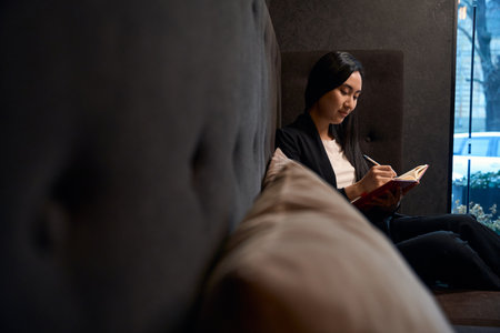 Asian woman writing down her thoughts and secrets into notebookの写真素材