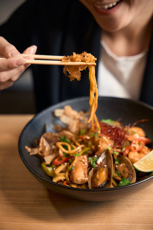 Close-up view happy Asian woman enjoying taste of fresh seafood ramenの写真素材