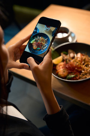 Woman taking photo of perfectly served and delicious seafood ramenの写真素材