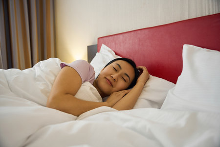 Serene young Asian lady sleeping in bedroom